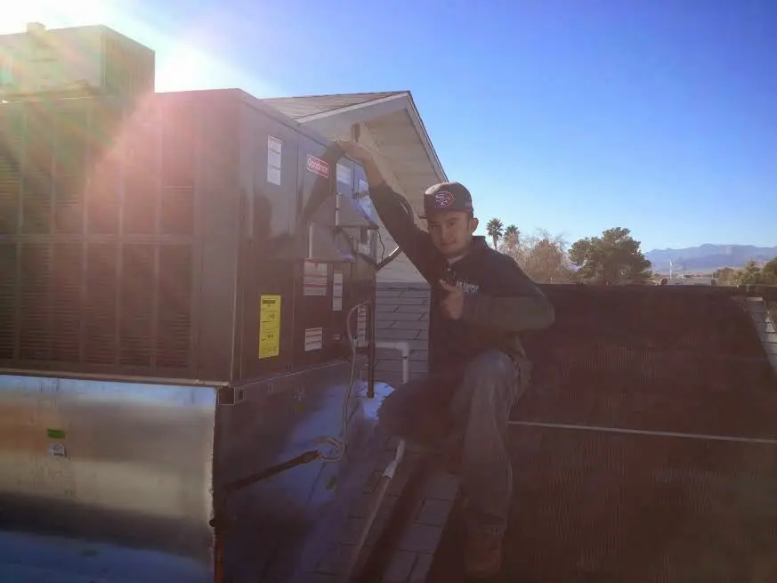HVAC technician performing Air Duct Cleaning on a rooftop unit in Dallas